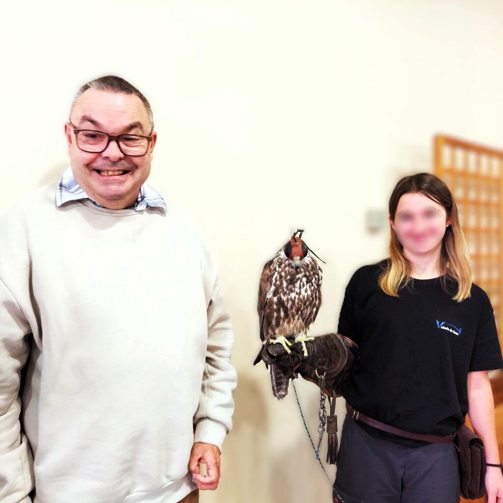Un résident du foyer de vie pose à côté d'un rapace
