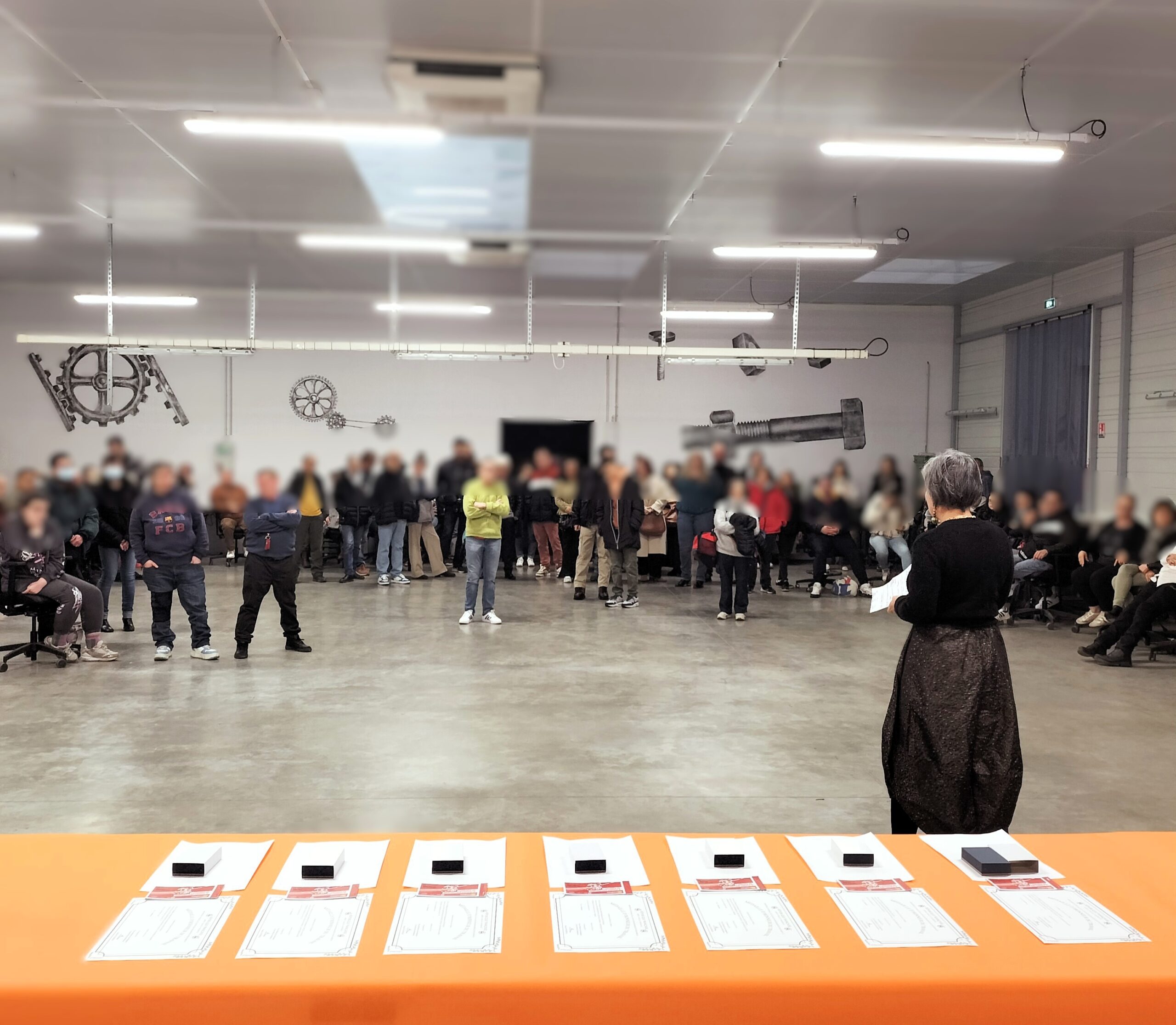 La directrice du CDAT est debout devant la la foule , derriere elle se trouve la table avec les médailles